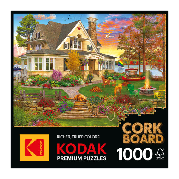 The ROSEART - KODAK PREMIUM CORK- LAKESIDE HOME, a 1000-piece jigsaw puzzle, features a serene lakefront scene with a cottage, porch, and garden amid autumn trees. Dogs and birds frolic in the yard beside a bicycle leaning against a tree by the peaceful lake.